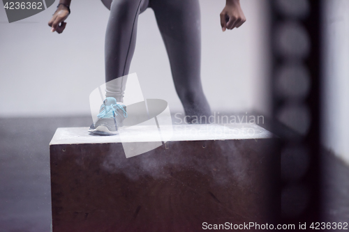 Image of black woman is performing box jumps at gym