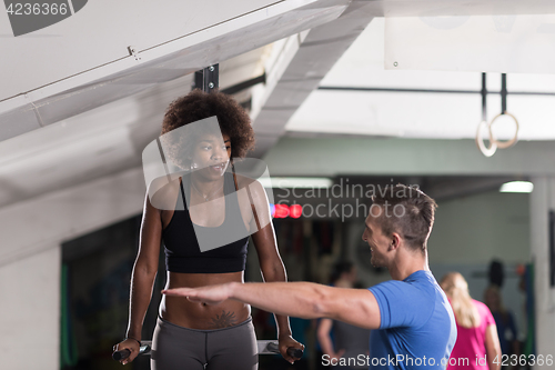 Image of black woman doing parallel bars Exercise with trainer