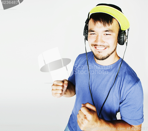 Image of young asian man in hat and headphones listening music on white b