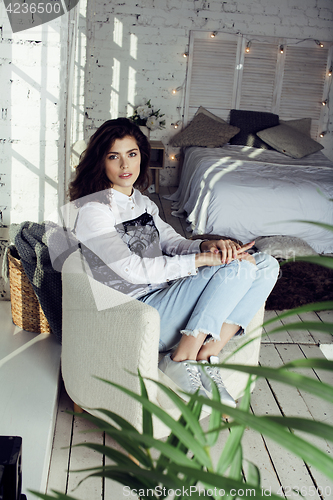 Image of young pretty woman in her bedroom sitting in chair, lifestyle people concept