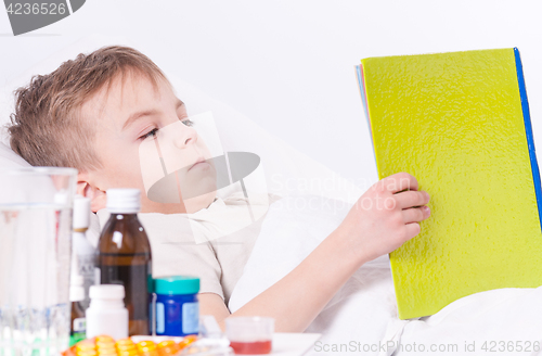 Image of Sick boy in bed reading book