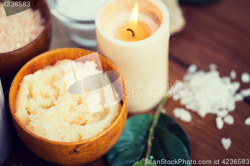 Image of close up of natural body scrub and candle on wood