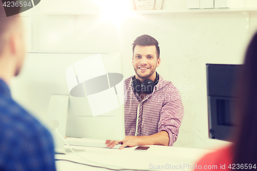 Image of happy young man or student with computer at office