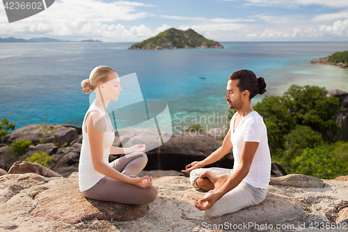 Image of happy couple doing yoga and meditating outdoors