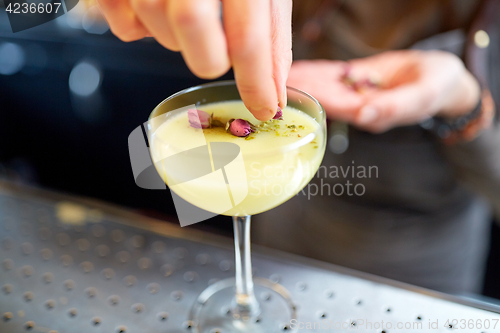 Image of bartender decorating cocktail in glass at bar