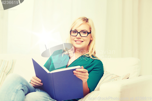 Image of young woman in glasses reading book at home