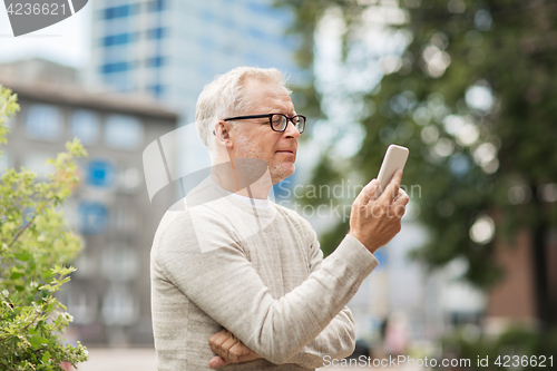 Image of senior man texting message on smartphone in city