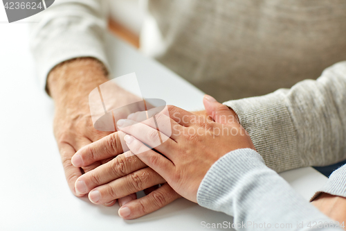 Image of close up of old man and young woman holding hands