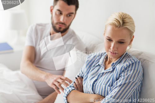 Image of unhappy couple having conflict in bed at home