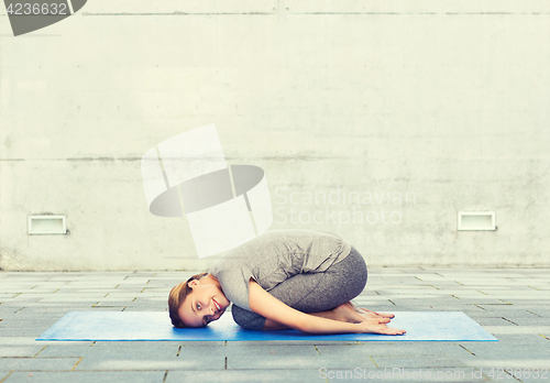 Image of happy woman making yoga in child pose on mat