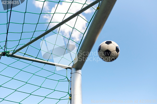 Image of soccer ball flying into football goal net over sky