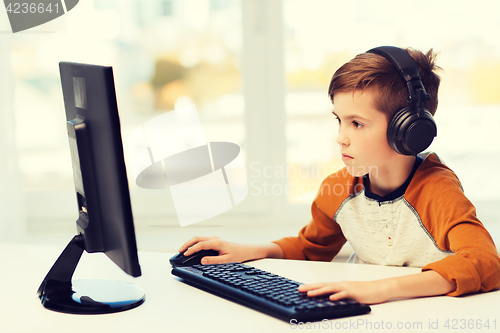 Image of boy with computer and headphones at home