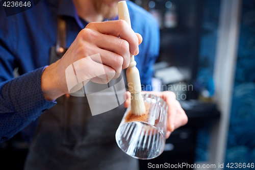 Image of close up of bartender with glass and brush at bar