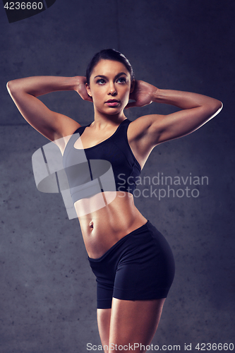 Image of young woman posing and showing muscles in gym