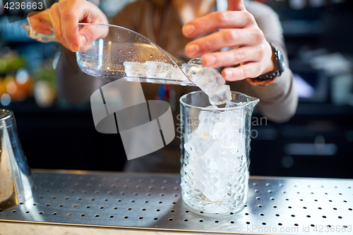 Image of bartender pouring ice into glass jug at bar