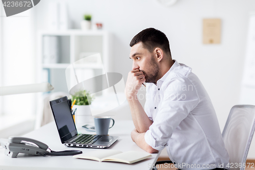 Image of businessman with laptop and notebook at office