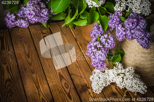 Image of Still-life with a bouquet of lilacs and a straw hat, close-up