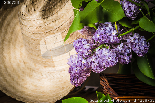 Image of Still-life with a bouquet of lilacs and a straw hat, close-up