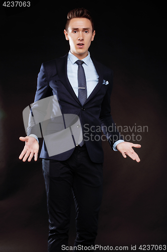 Image of young pretty business man standing on black background, modern h