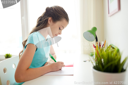 Image of girl writing to notebook at home