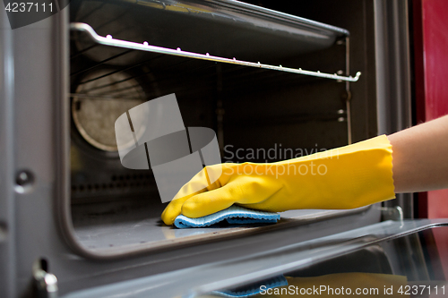 Image of hand with rag cleaning oven at home kitchen