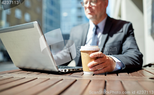 Image of senior businessman with laptop and coffee outdoors