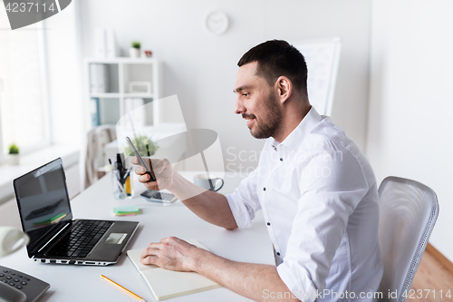 Image of businessman with smartphone and notebook at office