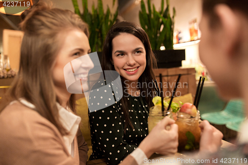 Image of happy friends clinking drinks at restaurant