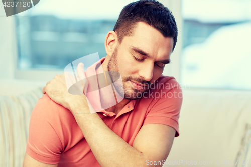 Image of unhappy man suffering from neck pain at home