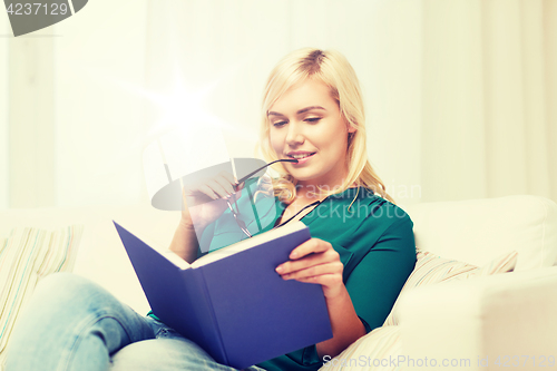 Image of young woman with glasses reading book at home