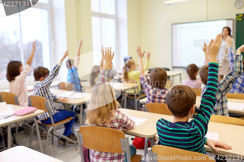 Image of group of school kids raising hands in classroom