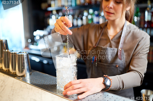 Image of bartender with cocktail stirrer and glass at bar