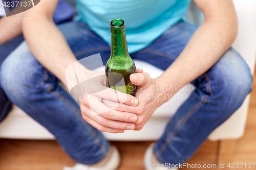 Image of men with beer bottles sitting on sofa at home