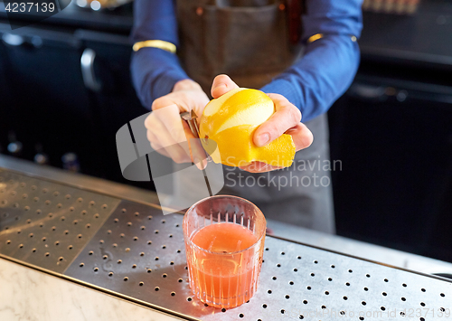 Image of bartender removing peel from lime at bar