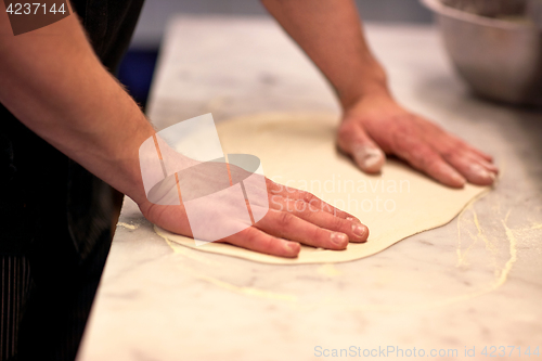 Image of chef hands preparing dough on table at kitchen