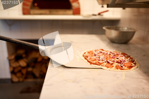 Image of peel taking pizza off table at pizzeria