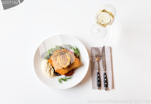 Image of fish salad and wine glass on restaurant table