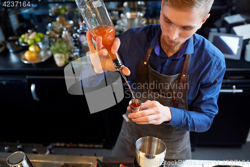 Image of barman pouring alcohol to cocktail jigger at bar