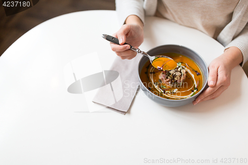 Image of woman eating pumpkin cream soup at restaurant