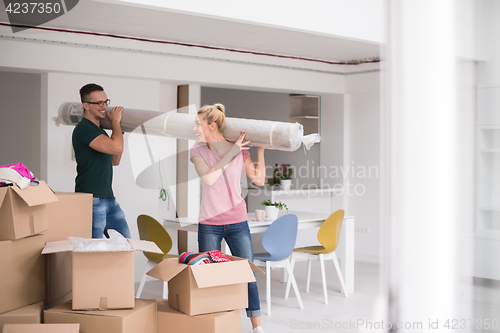 Image of couple carrying a carpet moving in to new home