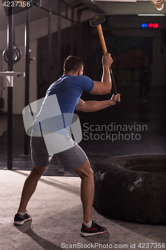 Image of man workout with hammer and tractor tire