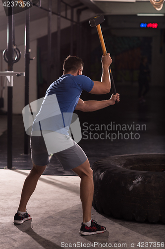 Image of man workout with hammer and tractor tire