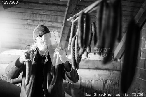 Image of Man drying sausages bw