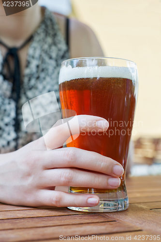 Image of hand holding glass of beer