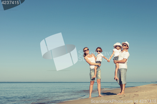 Image of Happy family standing on the beach at the day time.