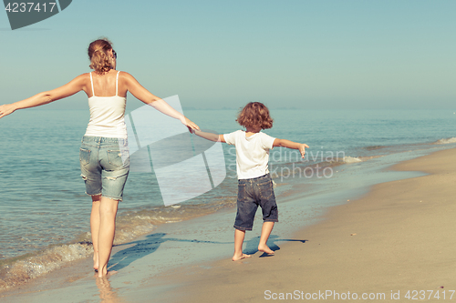 Image of Mother and son playing on the beach at the day time.