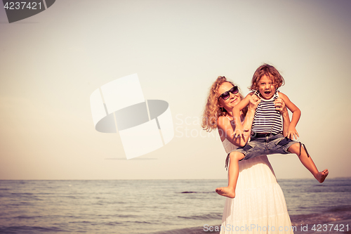 Image of Mother and son playing on the beach at the day time.