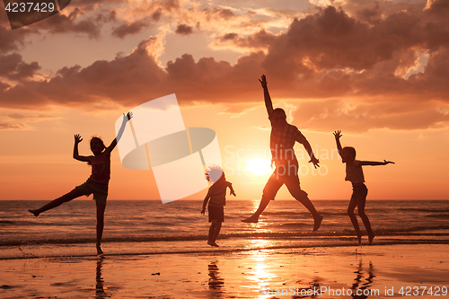 Image of Father and children playing on the beach at the sunset time. 