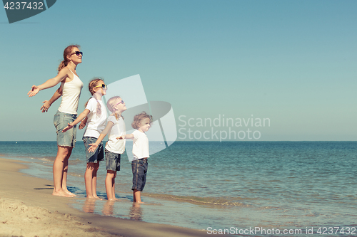 Image of Mother and  children playing on the beach. 