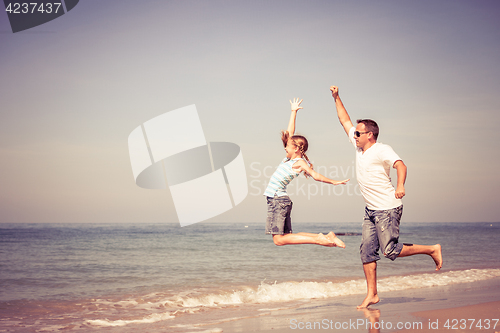 Image of Father and daughter playing on the beach at the day time.